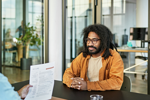 Person conducts interview with another person and reviews their resume